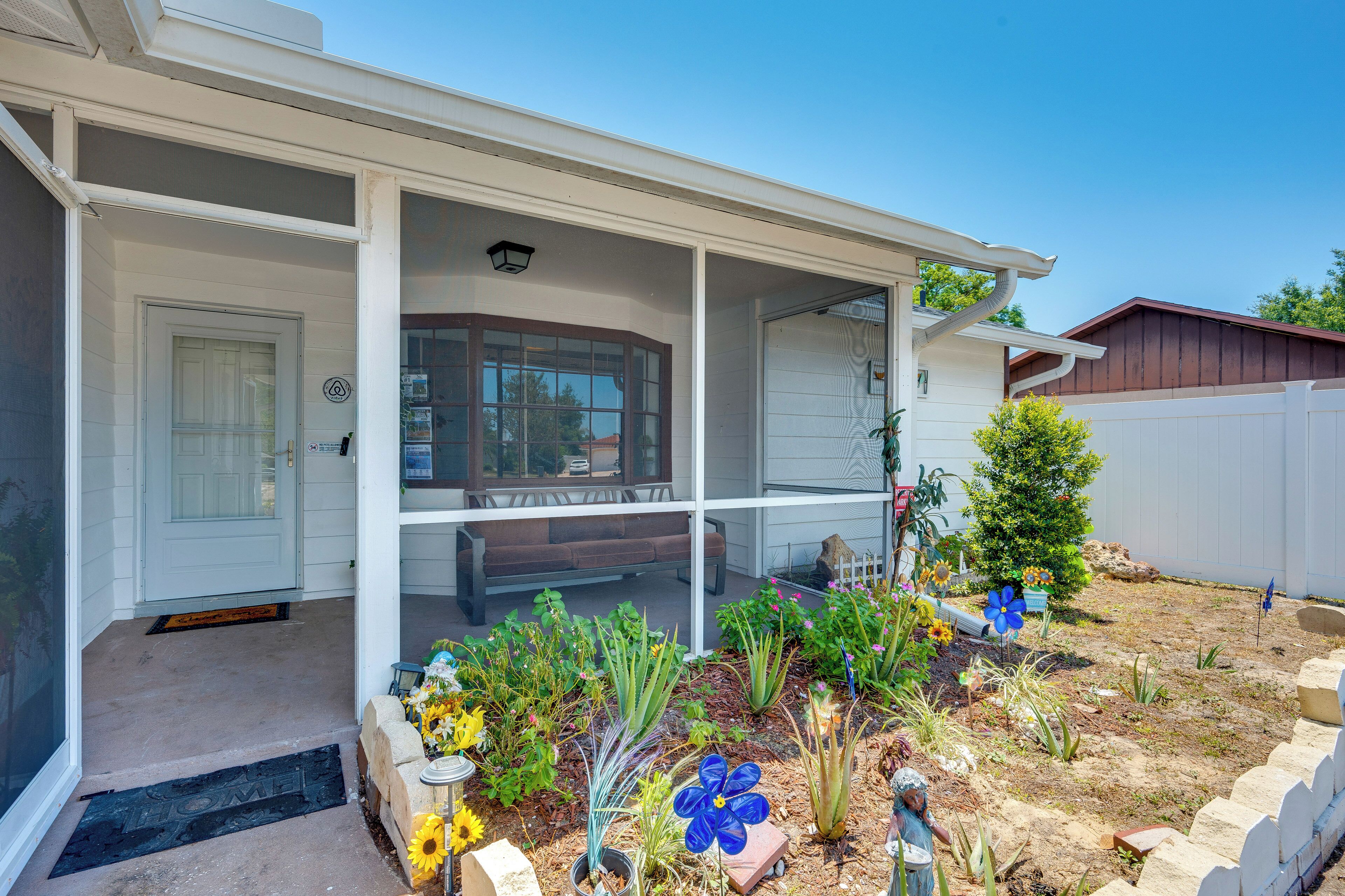 A house with a covered porch, a front door, and a garden with various plants and flowers.