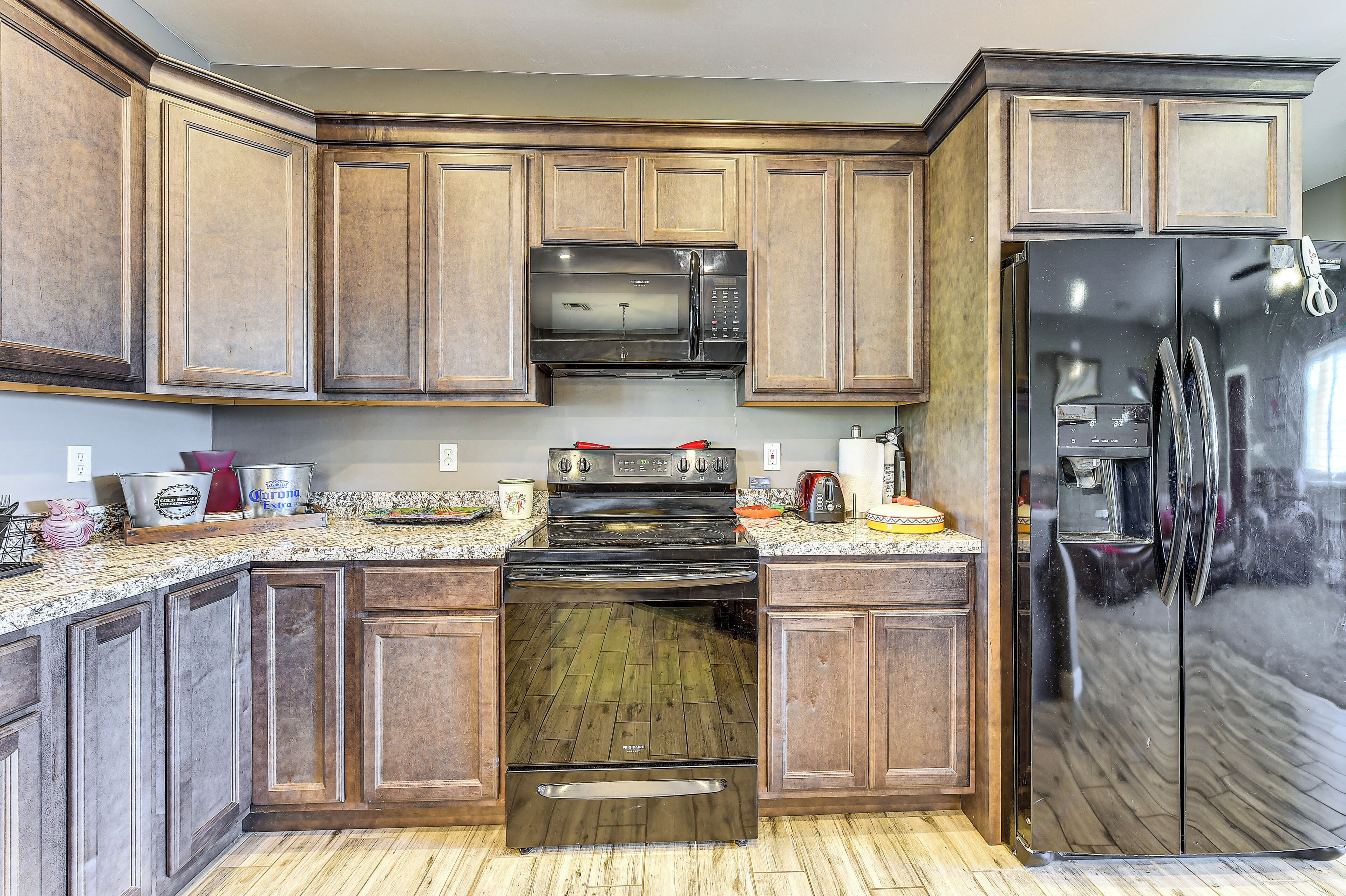 A kitchen with wooden cabinets, a stainless steel refrigerator, a microwave, and an oven.