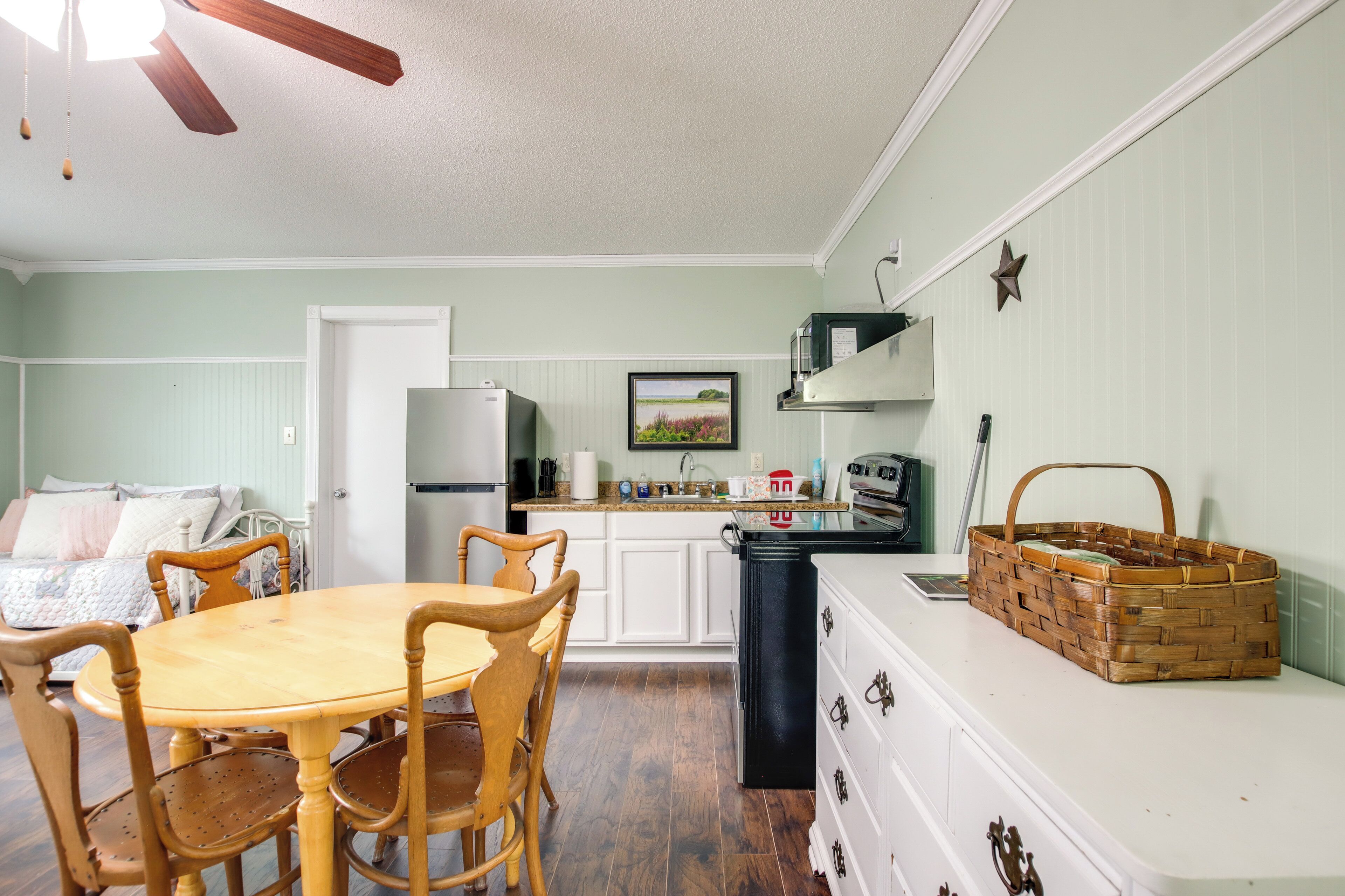 A kitchen with a wooden dining table and chairs, a refrigerator, a microwave, and a stove.