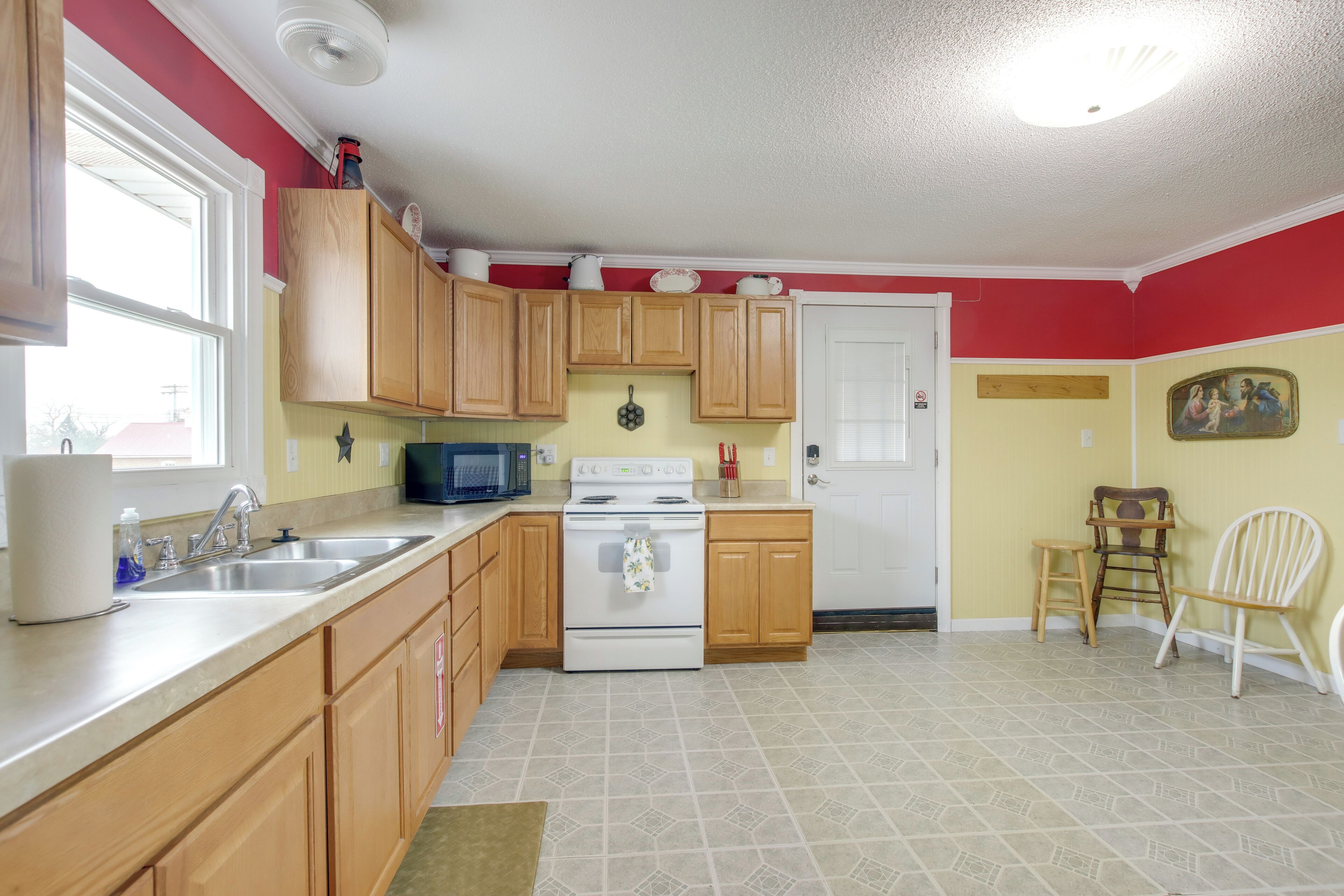A kitchen with wooden cabinets, a stove, a microwave, and a sink.