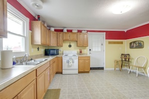 A kitchen with wooden cabinets, a stove, a microwave, and a sink. - Steps to Nauvoo Temple! 2-unit Family Combo (Nauvoo)