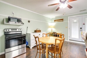 A kitchen with a built-in microwave, oven, and wooden dining table with chairs.