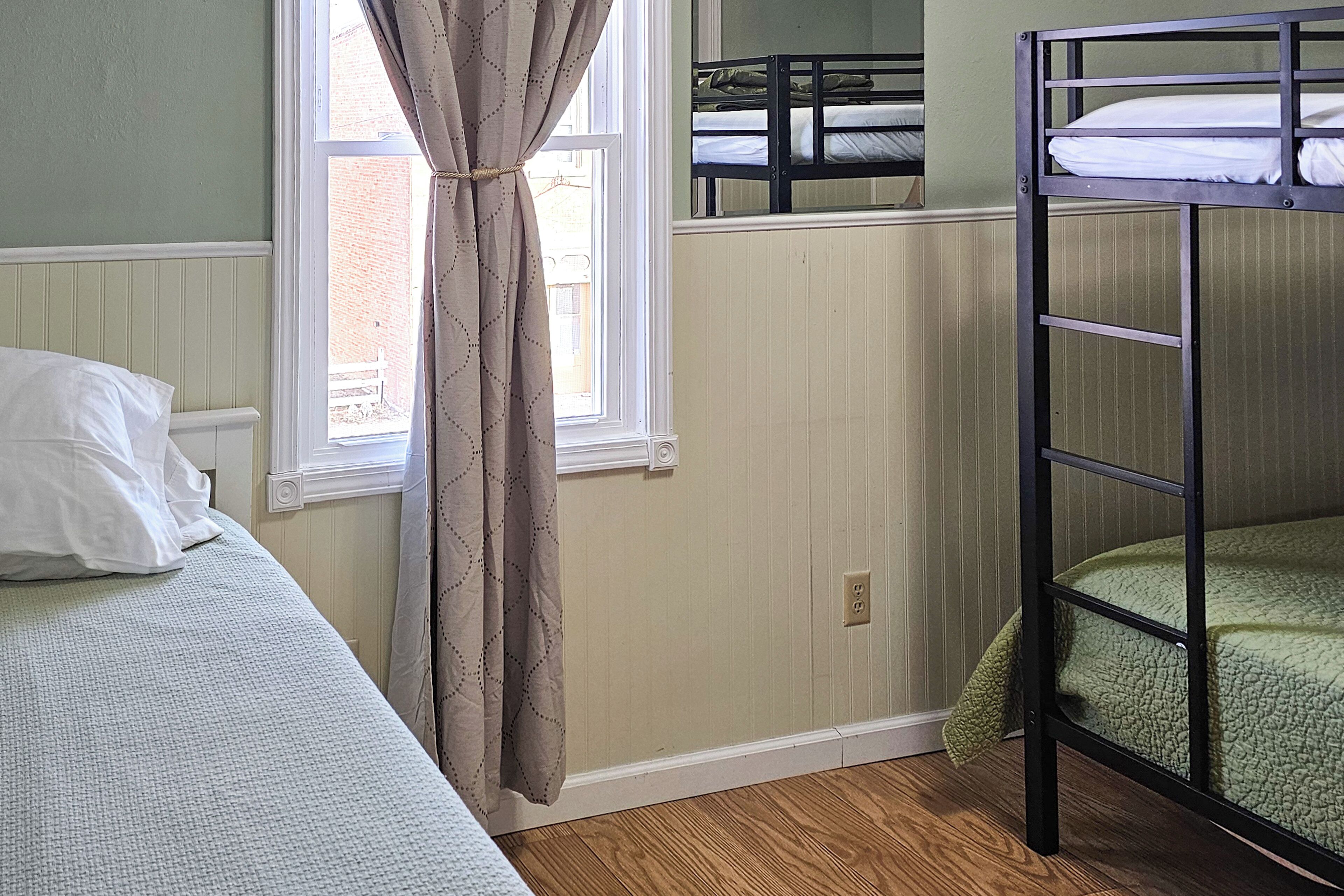 A bunk bed room with a window, a curtain, and a bed with a pillow.