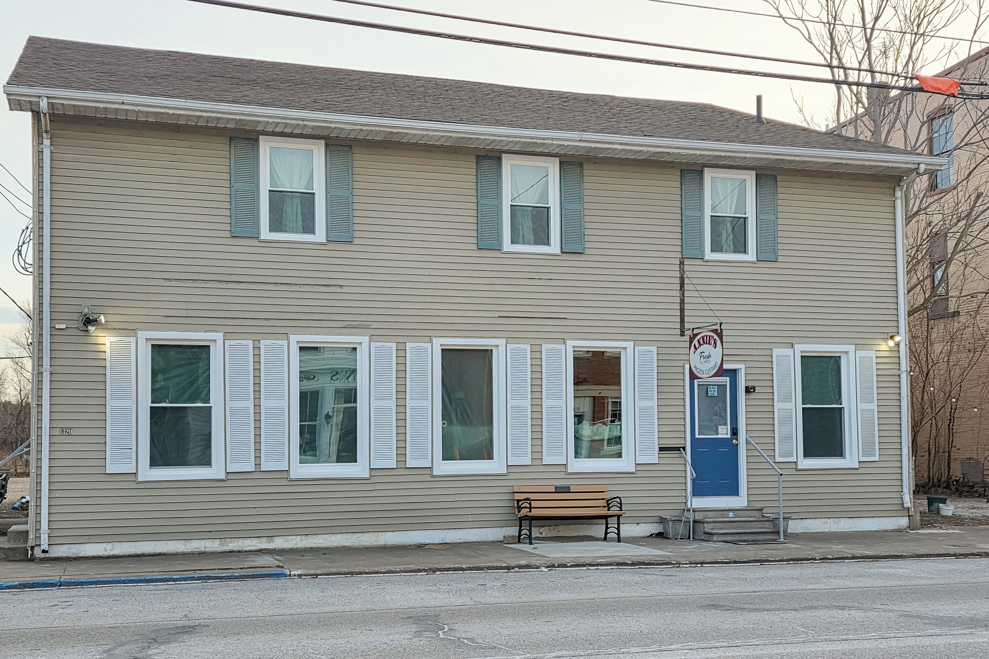 A two-story building with a blue door, a bench outside, and a sign above the door.