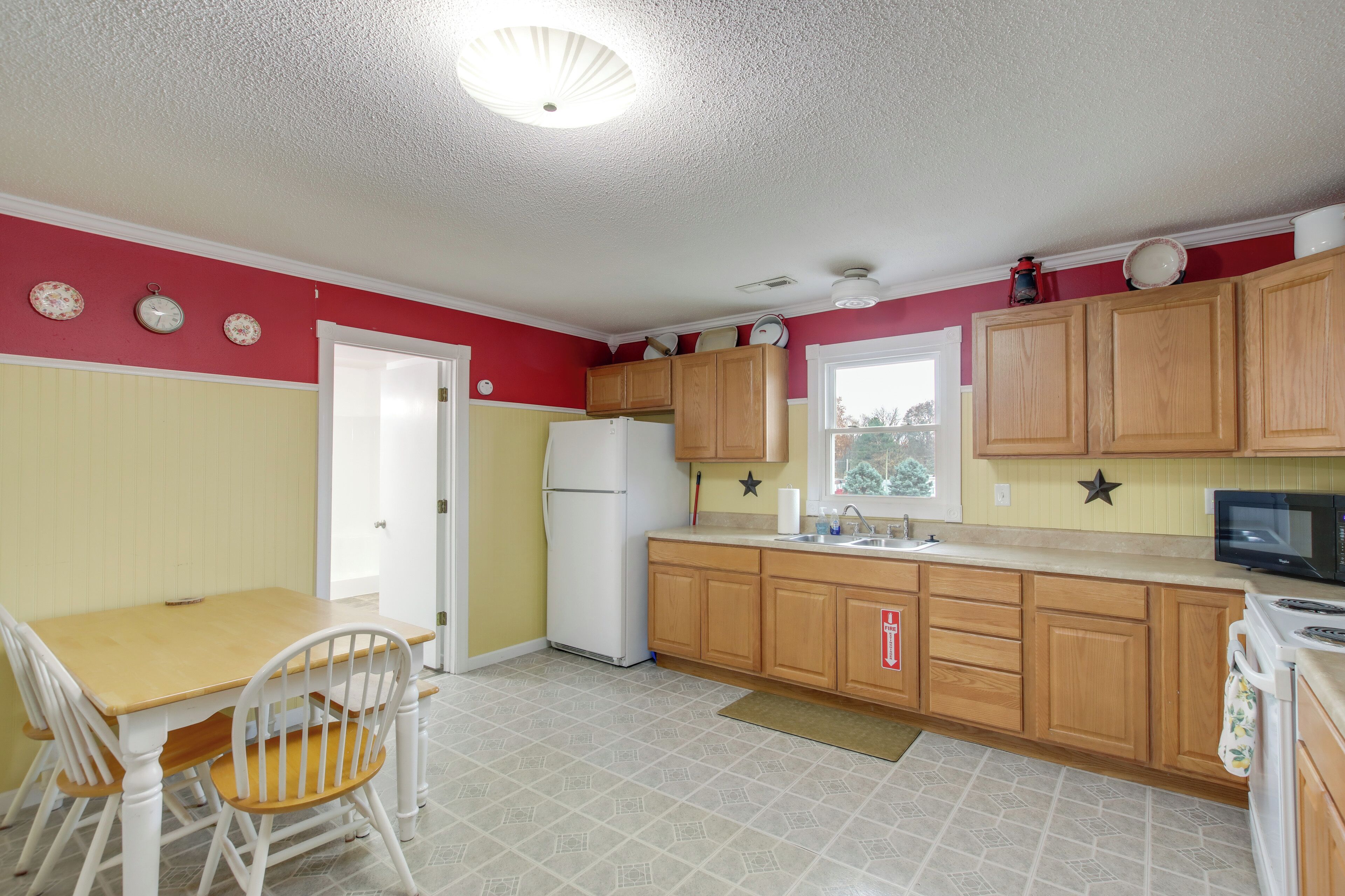 A compact kitchen with wooden cabinets, a refrigerator, a microwave, and a dining area with a table and chairs.