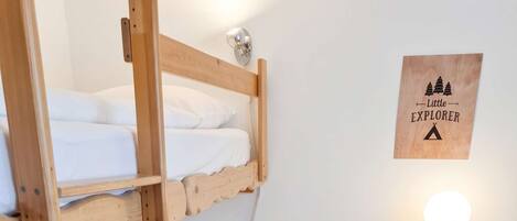 Habitación con literas, un escritorio, una lámpara, un armario y una decoración en la pared.