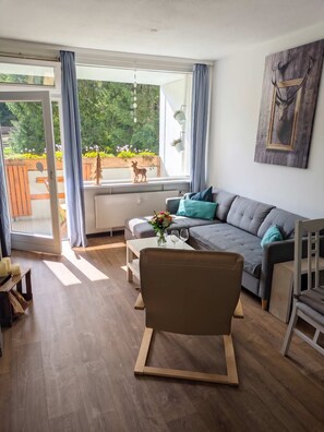 A modern living room with a grey sofa, wooden coffee table, and a wooden chair. - FeWo Tannenrauschen im Ferienpark Hahnenklee (Goslar)