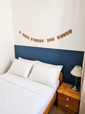 A bedroom with a bed, pillows, a nightstand, a lamp, and a wall banner. - FeWo Tannenrauschen im Ferienpark Hahnenklee (Goslar)