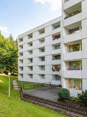 A multi-story building with balconies, a paved courtyard, and a surrounding fence. - FeWo Tannenrauschen im Ferienpark Hahnenklee (Goslar)
