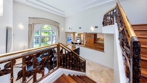 A staircase with a wooden handrail and a view of a dining area with a table and chairs. - 4 Bedroom Beautiful Home in Kahala (Honolulu)