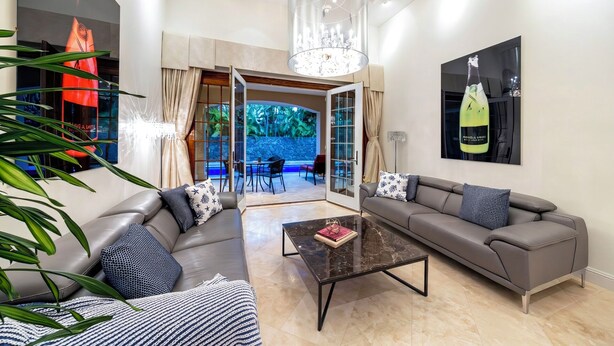 A modern living room with a sofa, coffee table, and a glass door leading to an outdoor area. - 4 Bedroom Beautiful Home in Kahala (Honolulu)