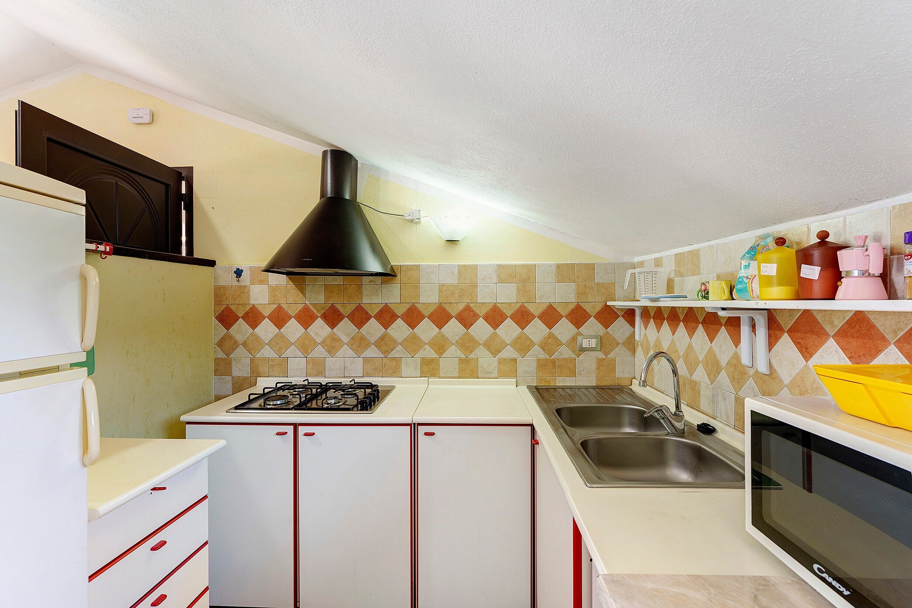 A compact kitchen with a gas stove, a sink, and a microwave.