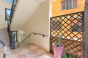A staircase with a handrail leading to an upper floor, a potted plant, and a gated area with a view of the outside. - Apartment 'Attico Bella Vista' with Mountain View, Wi-Fi and Air Conditioning (Siniscola)