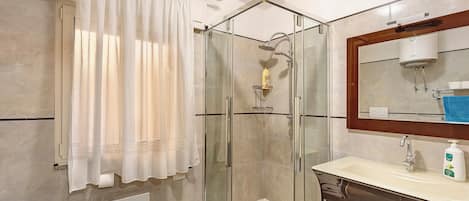 Une salle de bain avec une douche à parois de verre, un lavabo blanc, un miroir et un porte-serviettes.