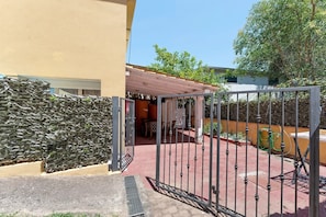 A gated entrance to a property with a stone wall, a covered patio area, and a paved walkway. - Apartment 'Casa 1 Camera Da Letto Piano Terra' with Private Terrace, Wi-Fi and Air Conditioning (Siniscola)