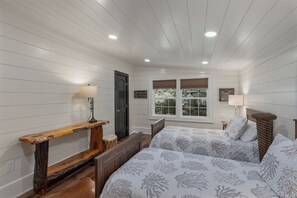 A bedroom with a bed, bedside tables, a window with blinds, and a door. - Highlands Hideaway | Close to Town, Pet Friendly, Custom Firepit (Highlands)