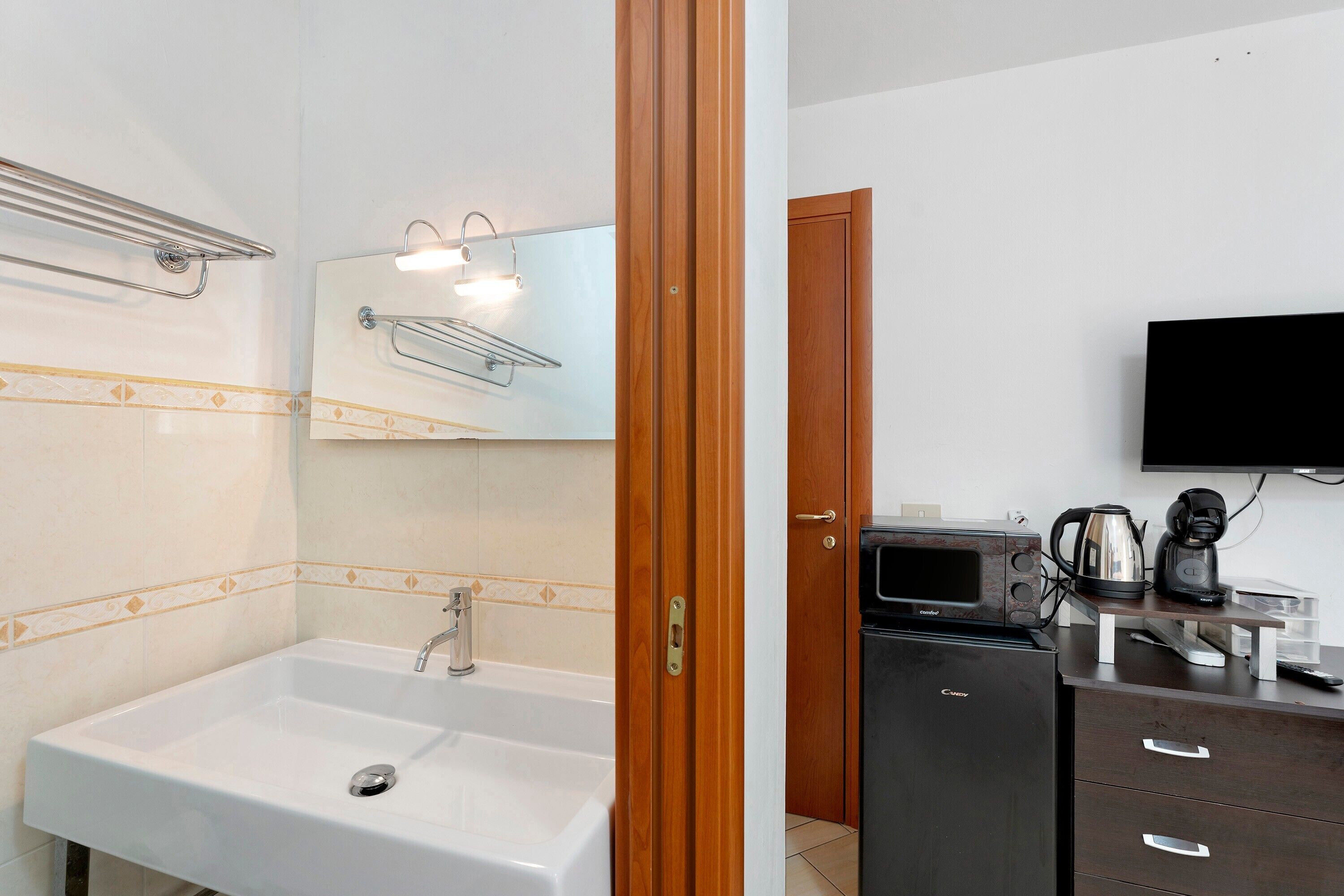 A bathroom with a sink, mirror, towel rack, and a coffee maker on a counter.