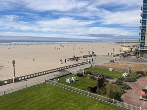 Aerial view of a beachfront property with direct sand access, landscaped grounds, and inviting outdoor amenities along the shoreline. - Downtown Oceanfront Seaside Retreat | • King Suite • Sleeps 4 (Seaside)
