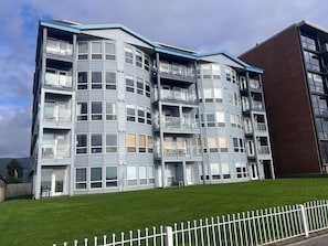 Un edificio residencial de varios pisos con balcones, ventanas amplias y techo plano.