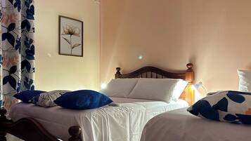 A double bed with a wooden headboard, a single bed with a wooden headboard, and a wall-mounted picture.