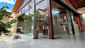 En moderne bygning med store glasvinduer, et trætag og en potteplante i entreen.