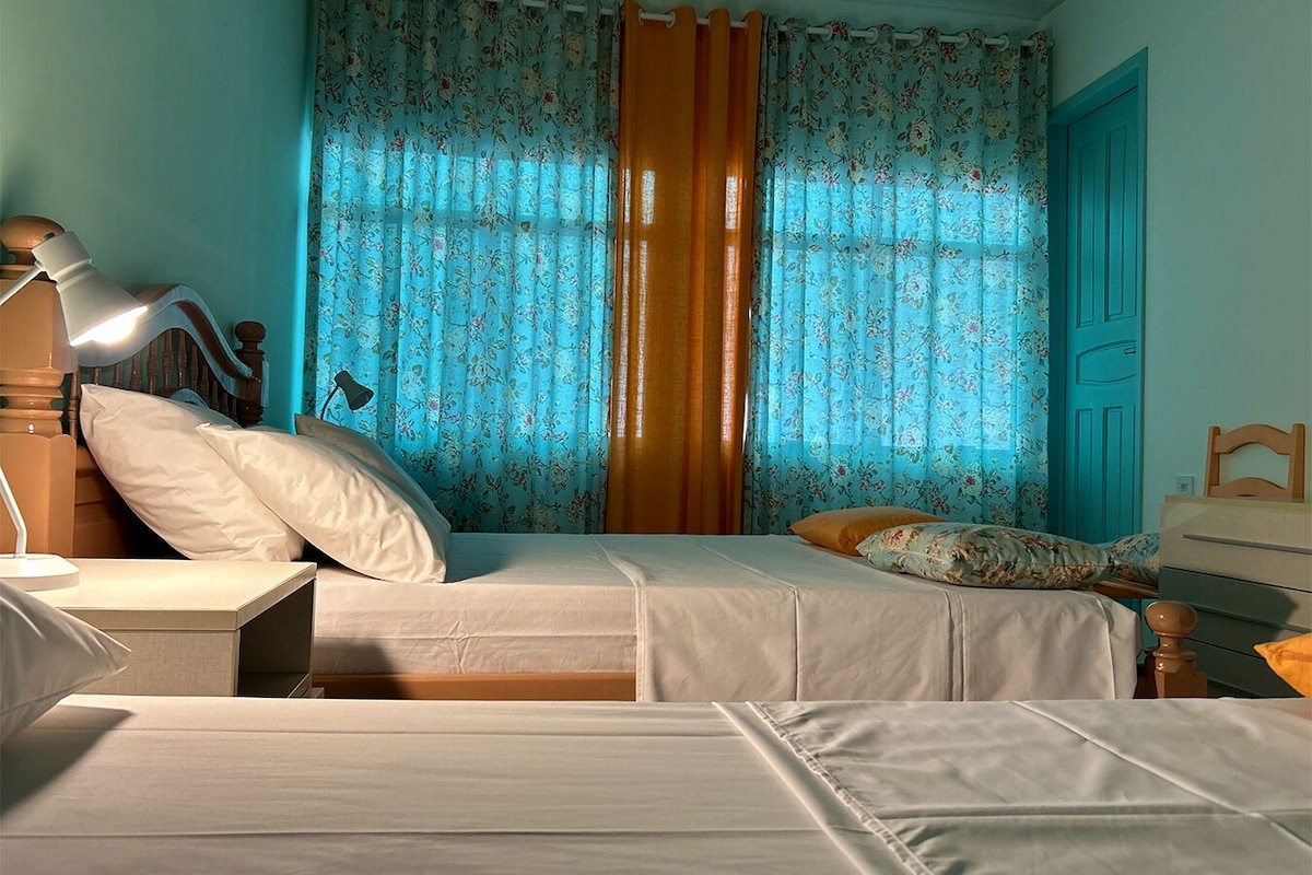 A bedroom with a bed, a nightstand, a lamp, and a dresser.