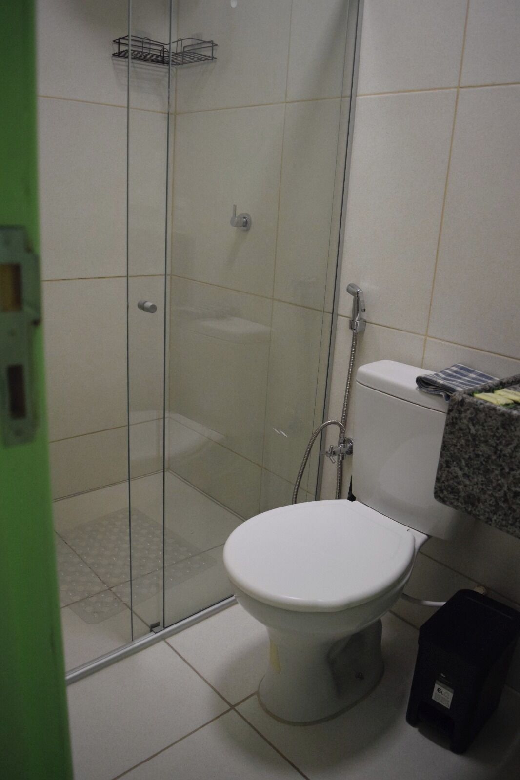 A bathroom with a toilet, a shower enclosure, and a tiled floor.