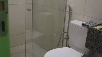 A bathroom with a toilet, a shower enclosure, and a tiled floor.