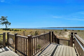 A wooden deck leading to a beach with a clear view of the water.
