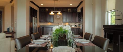 A dining area with a glass table set for six, surrounded by dark wooden chairs.