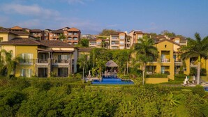 Ein Resort mit mehrstöckigen Gebäuden, einem zentralen Pool und üppiger Bepflanzung.