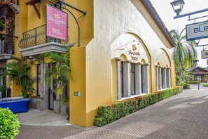 A hotel with a yellow facade, a balcony with a wrought iron railing, and a signboard advertising services. - Montecielo 4E 3 bdrs ocean view in Los Suenos (Herradura)