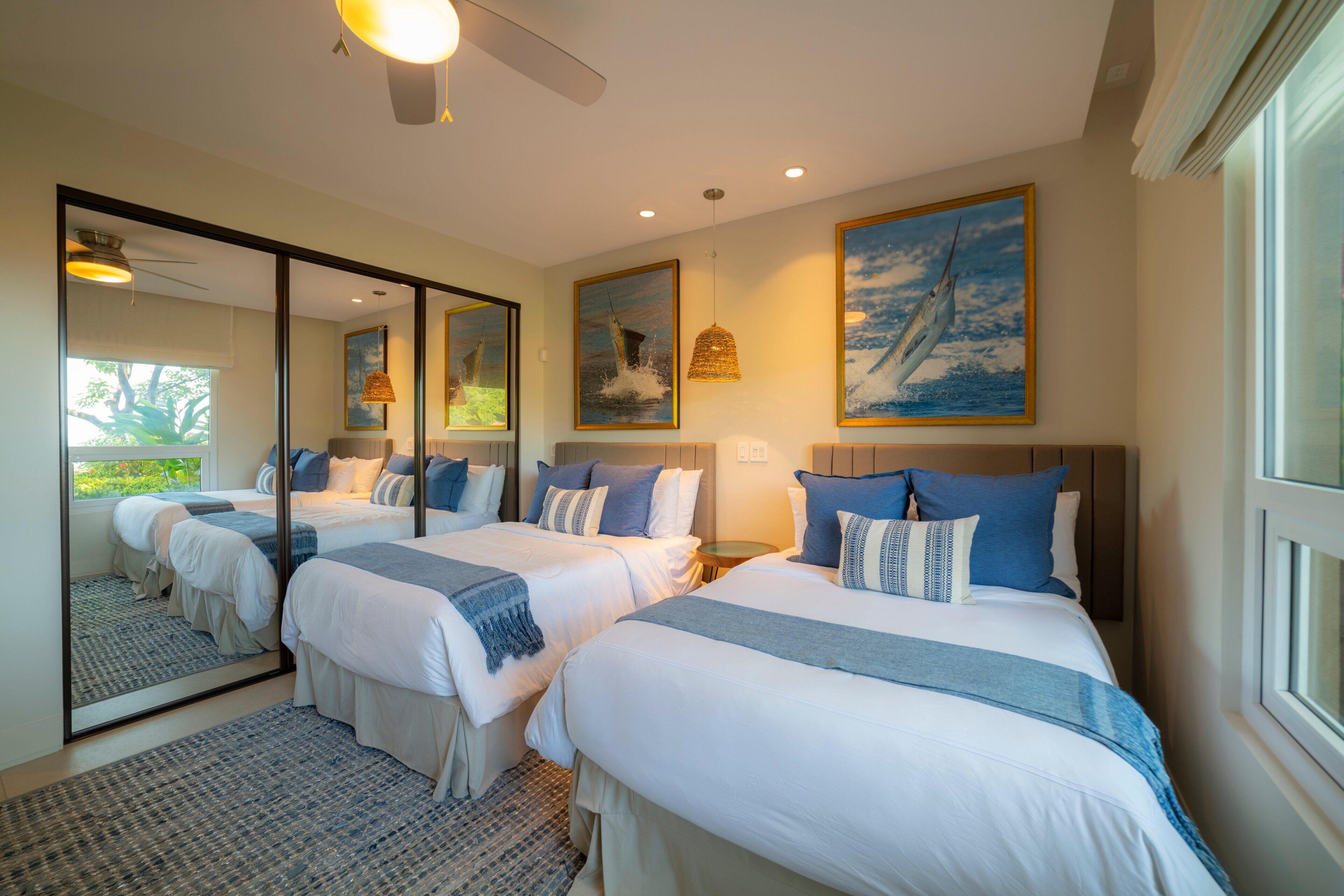 A hotel room with two beds, a large mirror, and artwork on the walls.