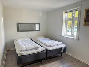 Ein Zimmer mit zwei Einzelbetten, einem Fenster mit Blick und einem Spiegel an der Wand.