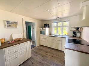 A compact kitchen with white cabinetry, a wooden countertop, a built-in oven, a coffee maker, and a window providing natural light. - 6 Person Holiday Home in Bedsted Thy (Bedsted)