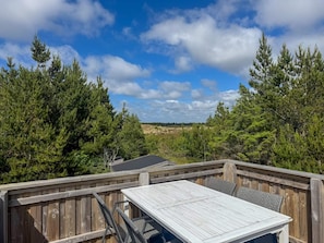 A wooden deck with a table and chairs, surrounded by dense evergreen trees and a clear sky. - 6 Person Holiday Home in Bedsted Thy (Bedsted)