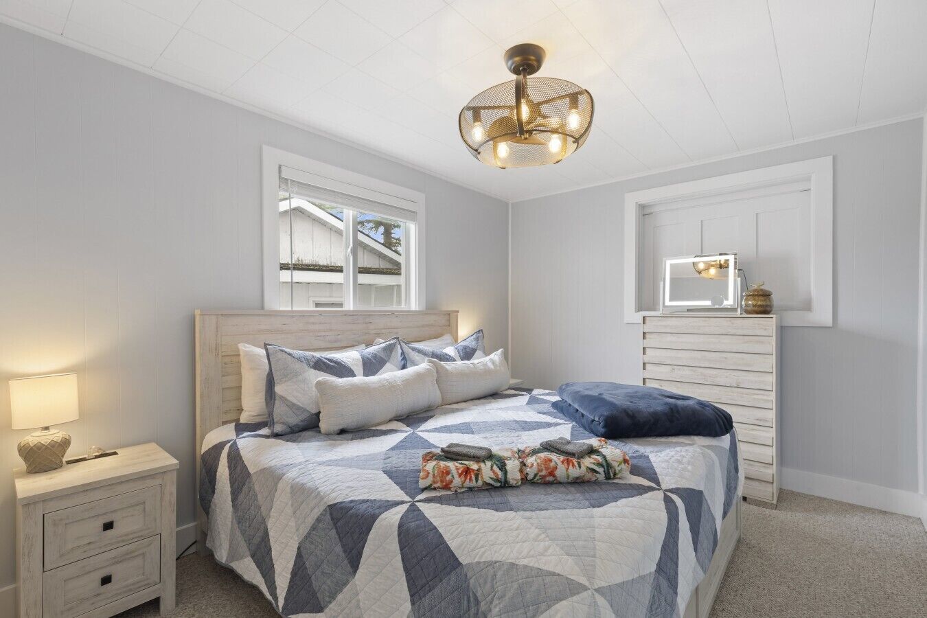 A bedroom with a bed, nightstand, dresser, and a ceiling light fixture.