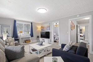 A modern living room with a flat-screen TV, a coffee table, and a sofa.