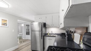 A modern kitchen with a stainless steel refrigerator, a gas stove, and white cabinetry.