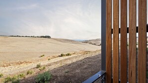 A view from a balcony with a metal railing, overlooking a dry, hilly landscape with sparse vegetation. - Studio on Forktree – Modern Coastal Retreat (Carrickalinga)