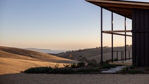 A modern building with a sloped roof, large windows, and a view of rolling hills. - Studio on Forktree – Modern Coastal Retreat (Carrickalinga)