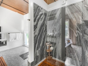 Casa de banho moderna com paredes de mármore, compartimento de chuveiro em madeira e área de lavatório visível.