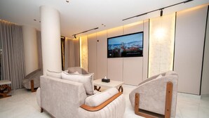 Una sala de estar moderna con un sofá, un sillón y un televisor de pantalla plana montado en la pared.