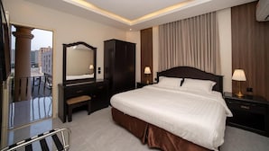 Habitación de hotel con una cama grande, un armario, un espejo, lámparas de noche y un balcón.