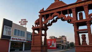 A traditional Indian gateway with intricate carvings, a modern hotel building with signage, and a clear sky. - Hotel Dev Shree Palace (Ujjain)