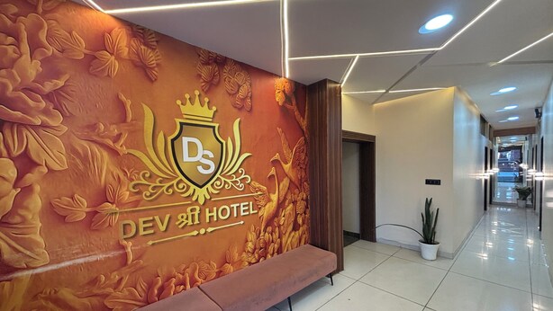 A hotel lobby with a large wall mural, a bench, and a tiled floor. - Hotel Dev Shree Palace (Ujjain)