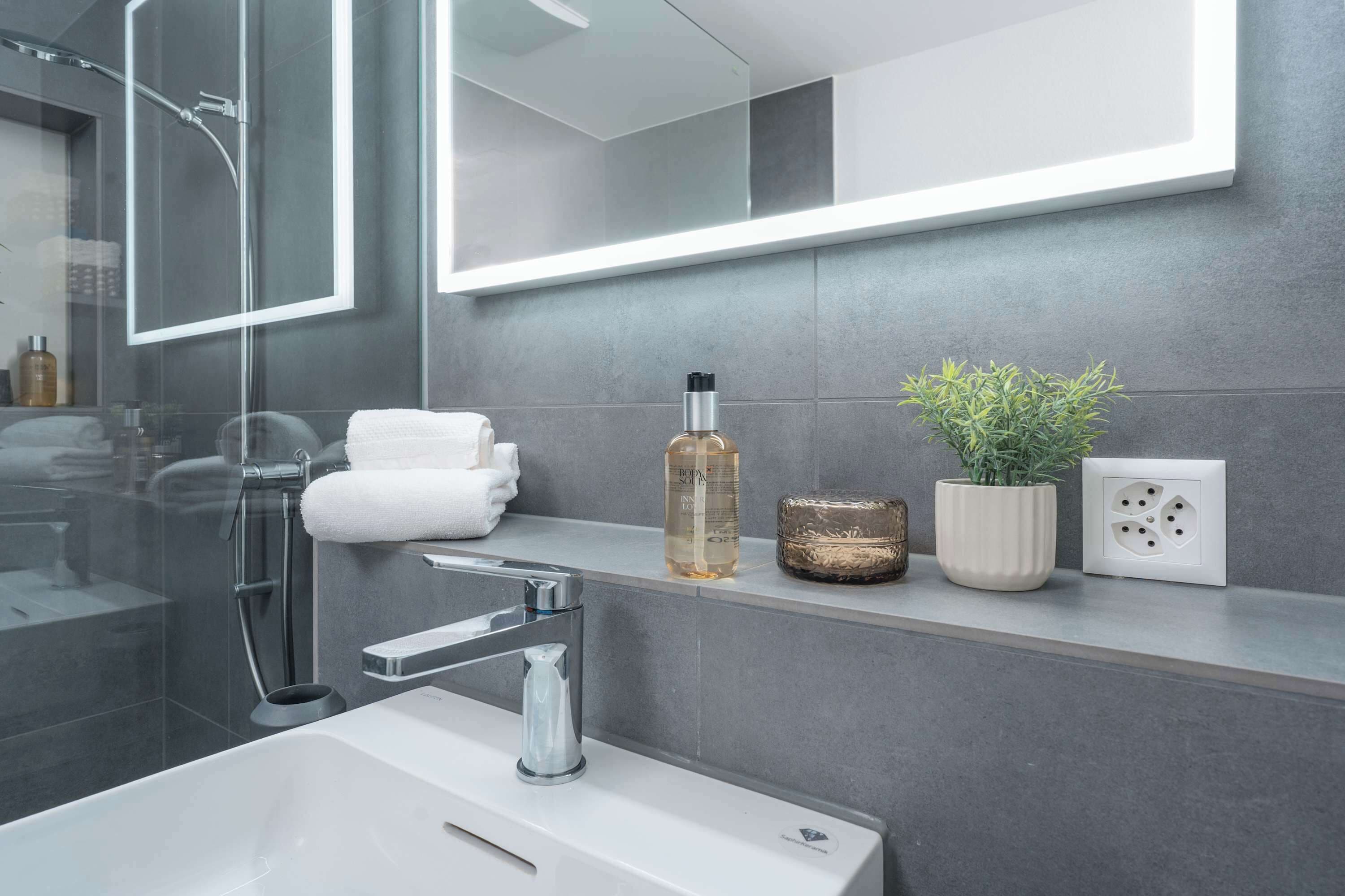 Stylish bathroom with illuminated mirror and modern sink.
