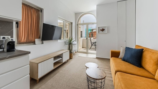 Un salon moderne avec un canapé, un téléviseur et une petite table.