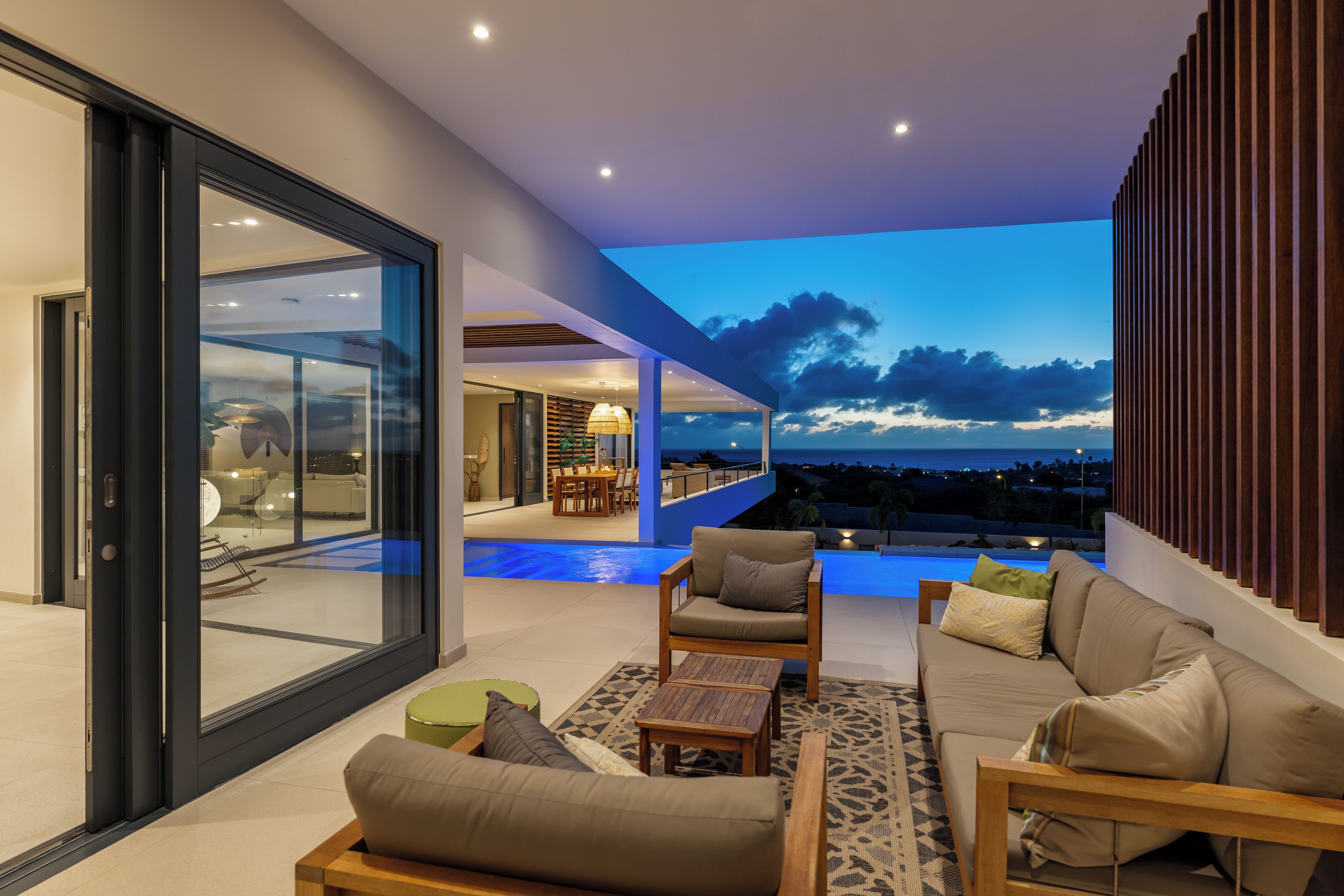 Un espacio de estar moderno con piscina, asientos y vista al cielo.