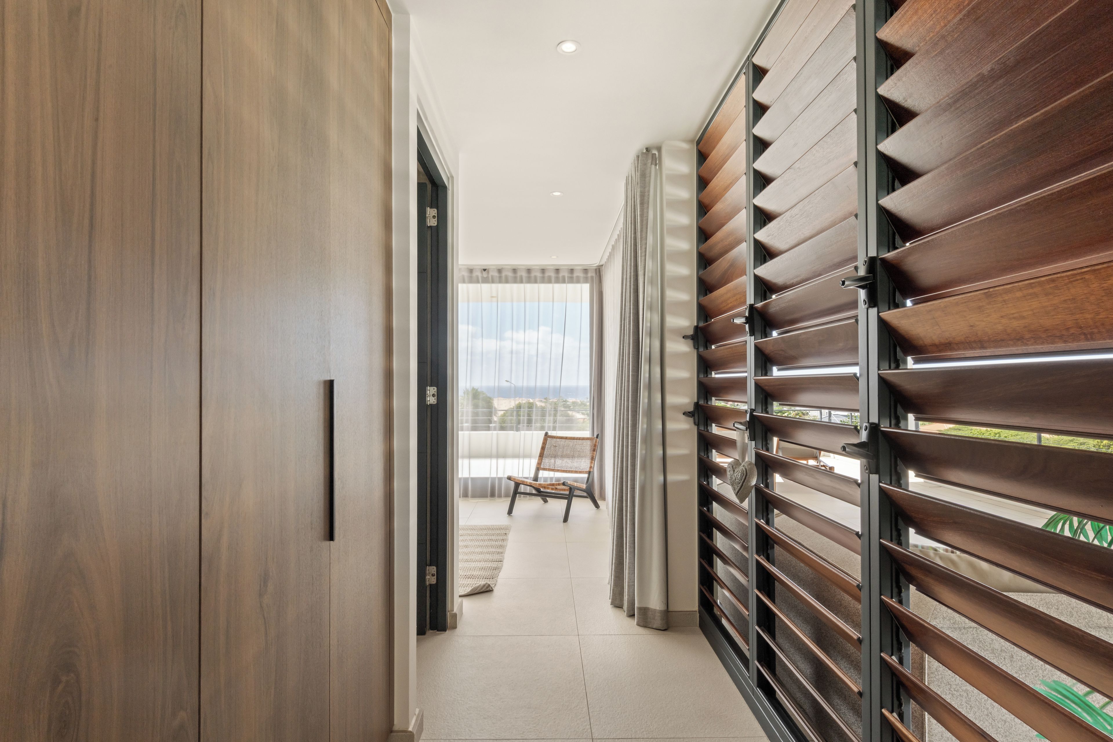 Een gang met een houten garderobe, een stoel en uitzicht op het buiten.